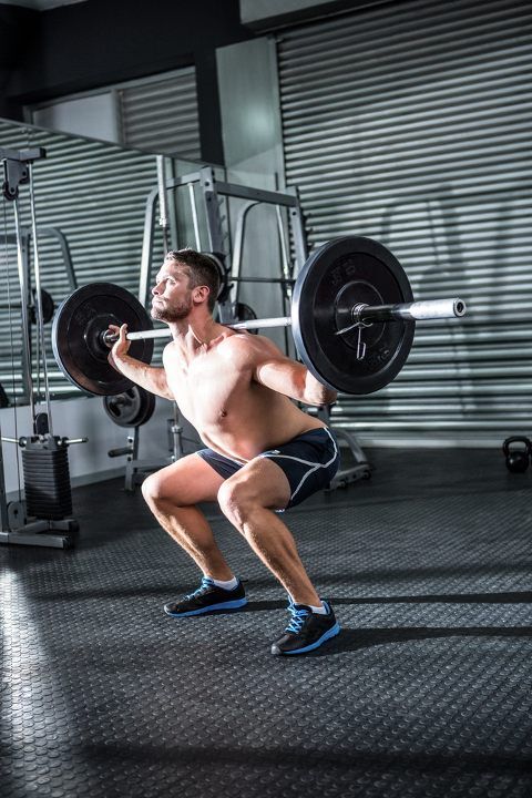 Man doing barbell squats at the gym