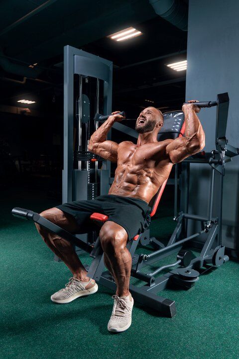 Man doing intense workout with shoulder press machine