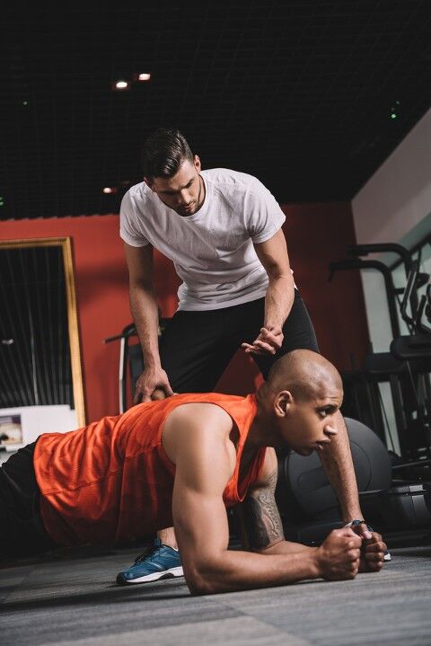 Man doing plank exercise with a trainer