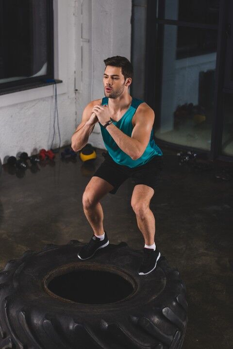 Man doing squats on a tire