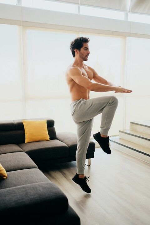 Man performing the high knees exercise at home 