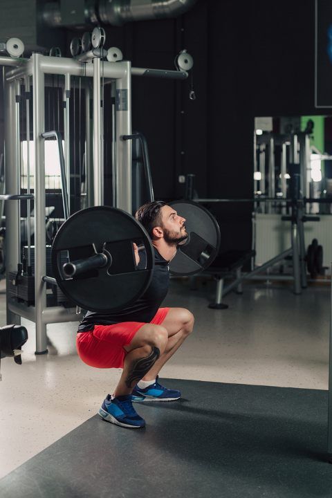 Man doing barbell squats at the gym